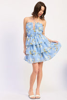 Woman wearing a blue floral ruffle tiered mini dress against a white background front view