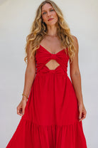 Woman wearing a red dress with cut-out design against a white background, close up of bodice.