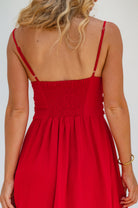 Red dress with thin straps worn by a person on a white background, closeup of back view