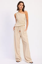 Model wearing beige one shoulder top with wide leg pants
