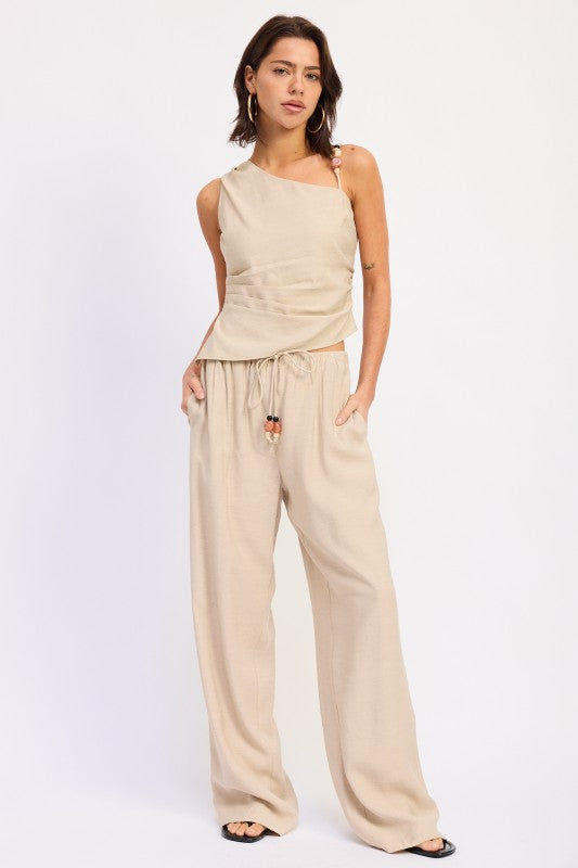 Model wearing beige one shoulder top with wide leg pants