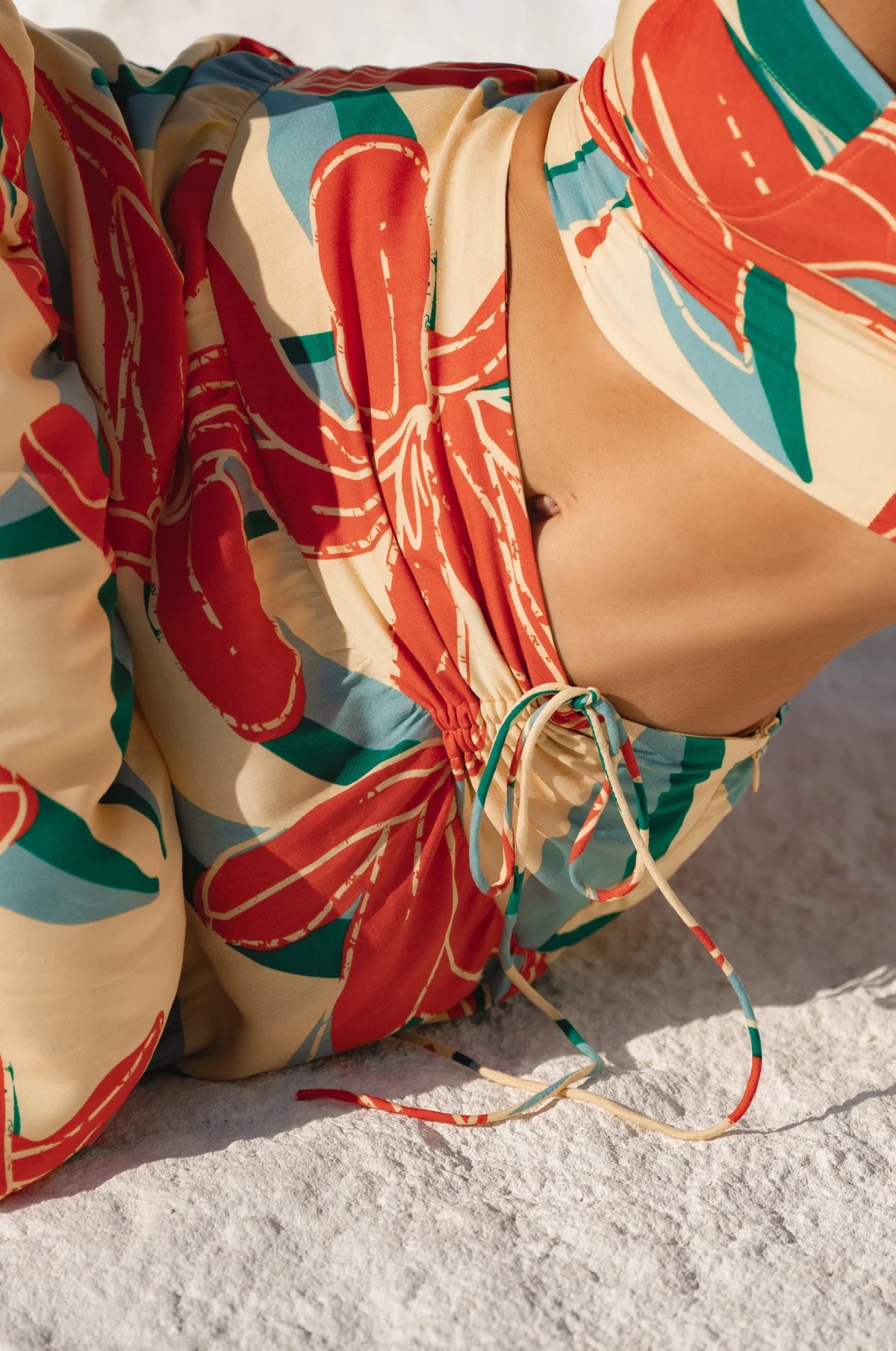 Closeup of bodice of two-piece matching cropped top and maxi skirt on a sandy surface.