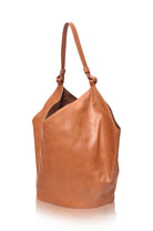 Tan leather handbag on a white background, side view