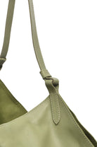 Close-up of a green leather bag with strap on a white background