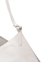 Close-up of a light white handbag with a strap on a white background