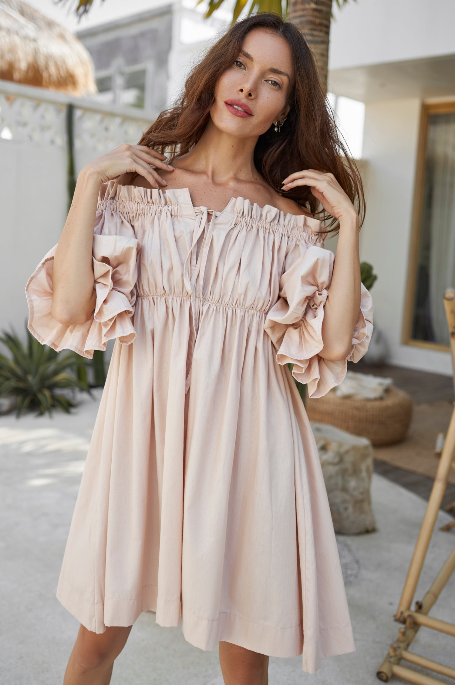 Woman wearing a light pink off-shoulder dress in an outdoor setting.