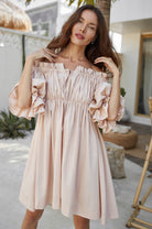 Woman wearing a light pink off-shoulder dress in an outdoor setting.