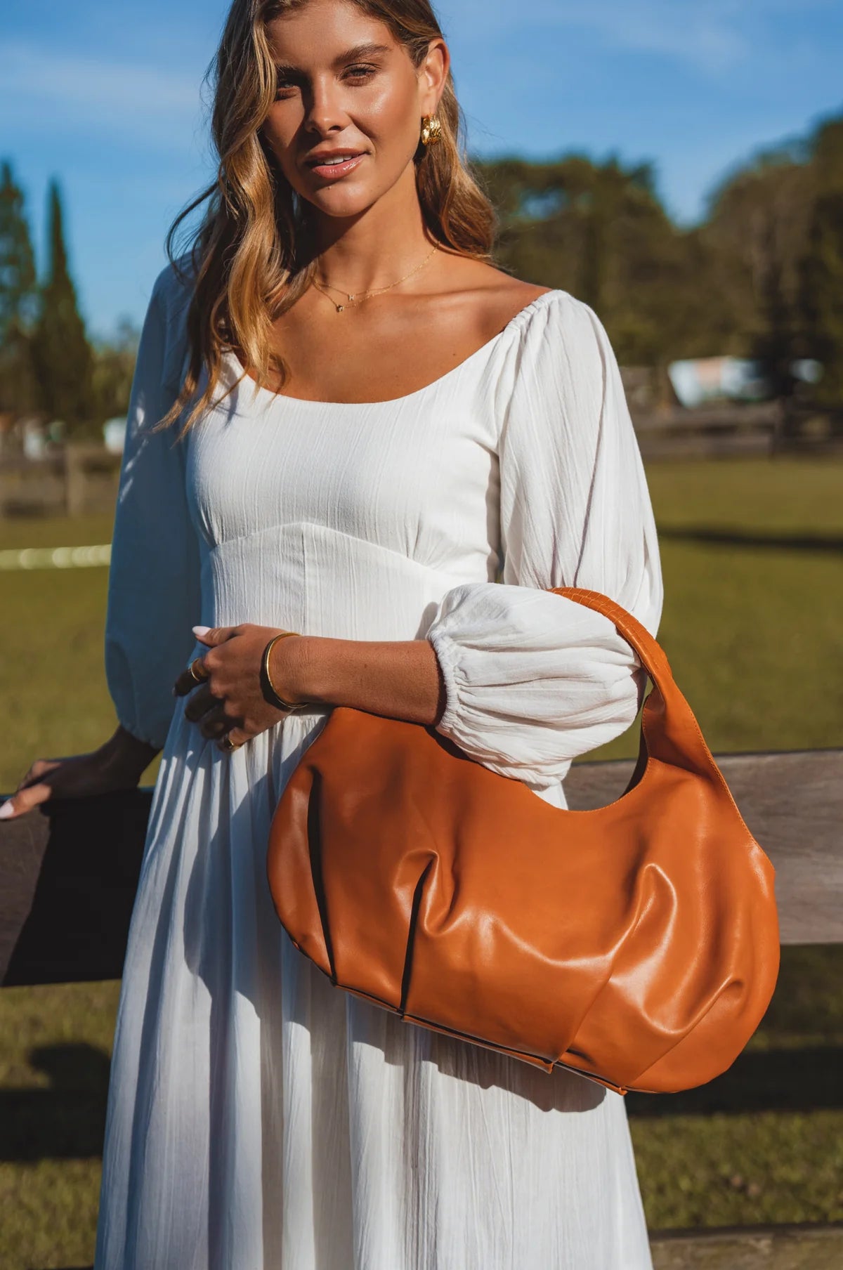 Woman holding a tan leather handbag outdoors