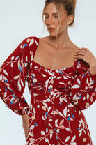Woman wearing a red floral dress against a white background