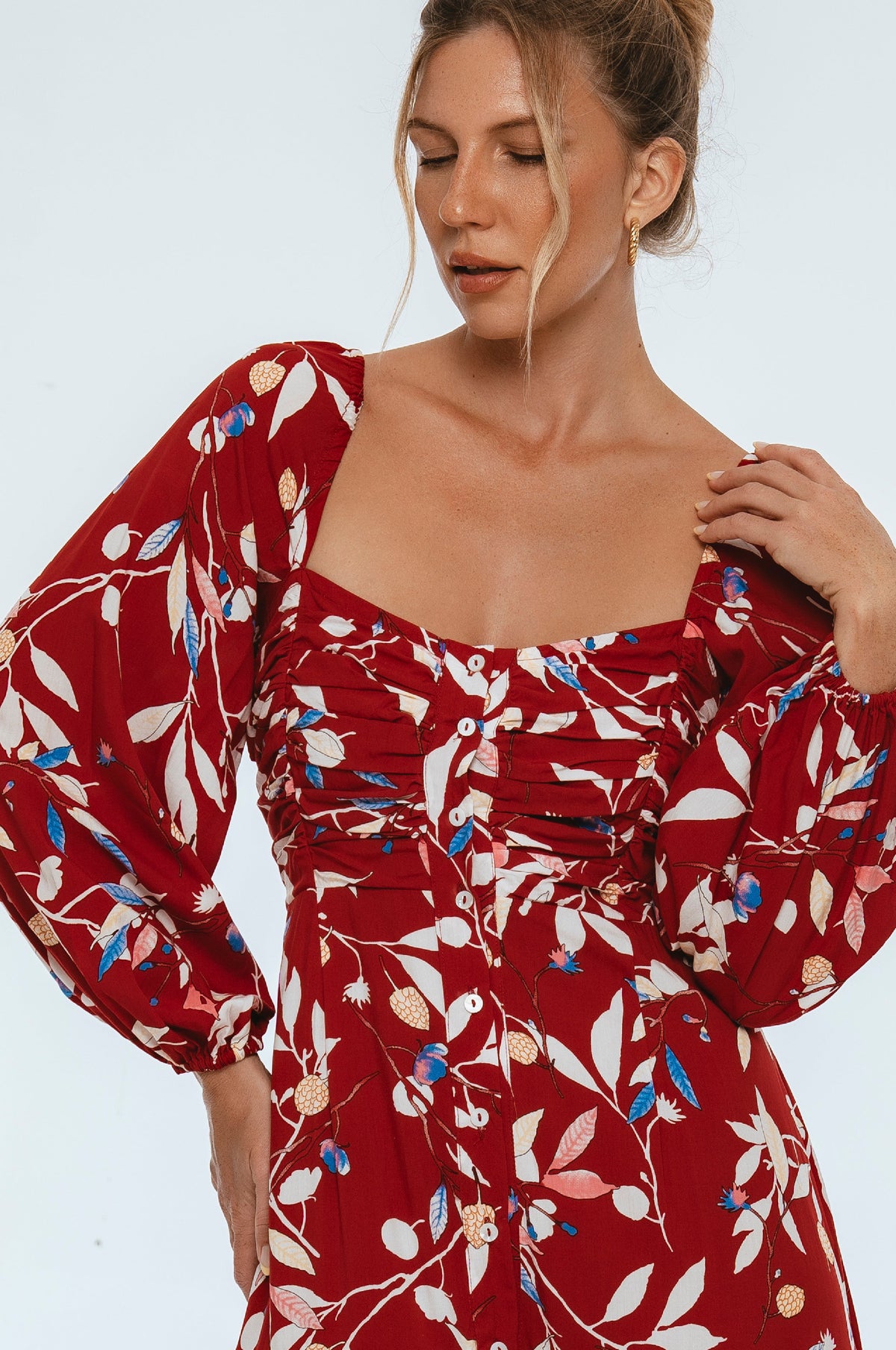 Woman wearing a red floral dress against a white background