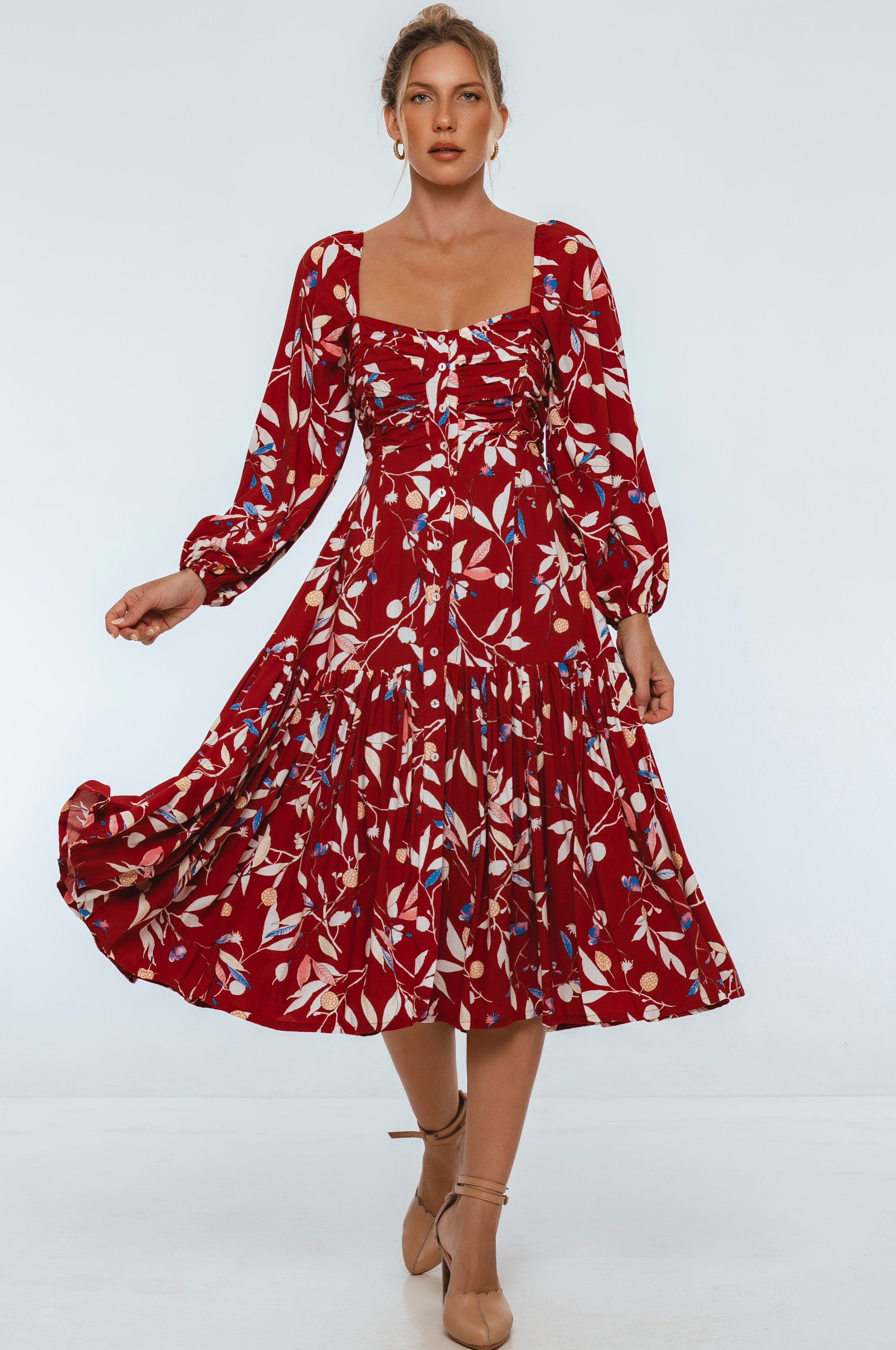 Woman wearing a red floral midi dress on a white background
