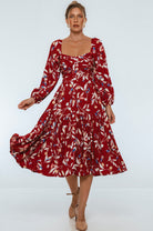 Woman wearing a red floral midi dress on a white background