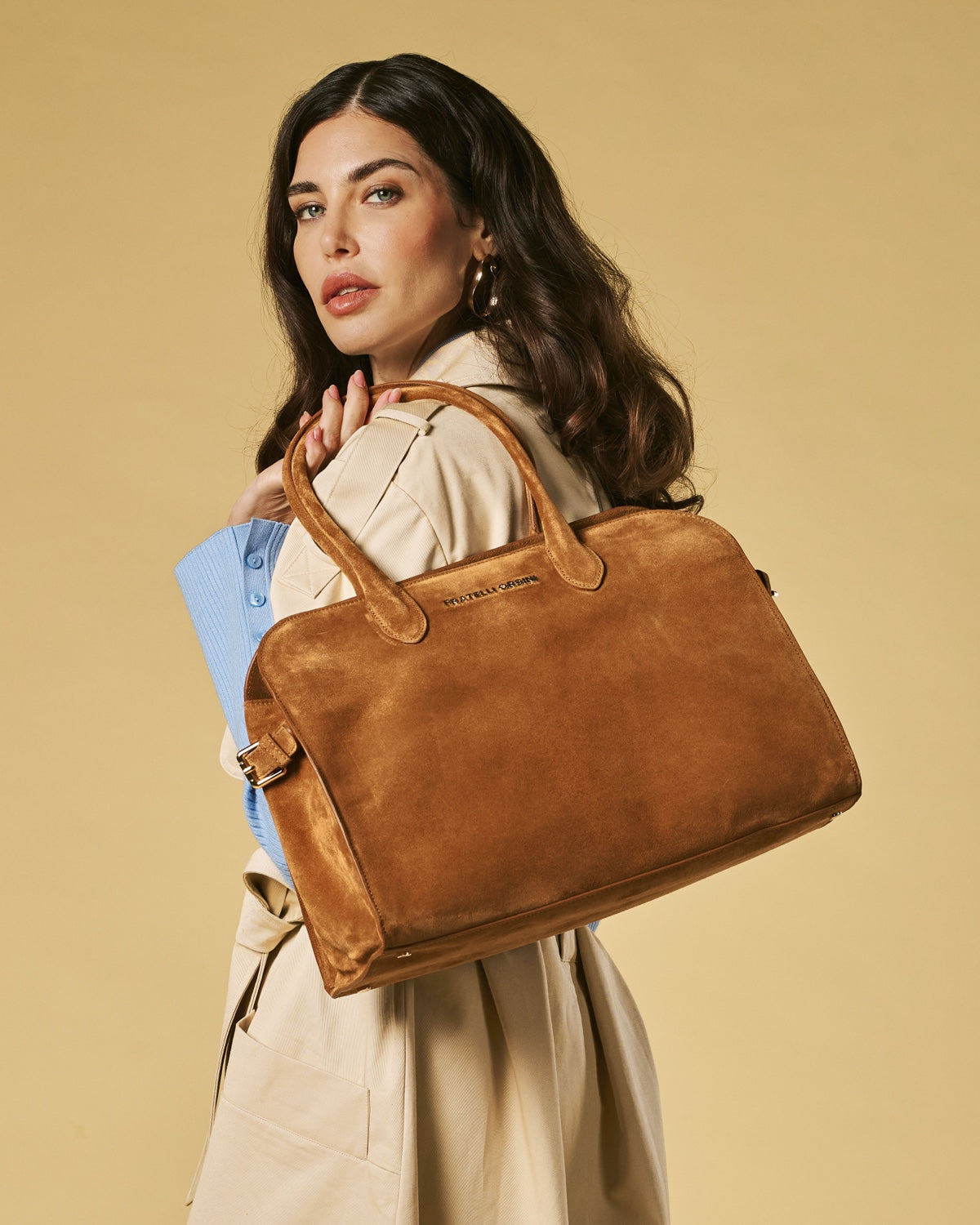 Woman holding a brown leather bag against a beige background