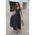 Model wearing black polka dot halter maxi dress with open back and front slit.
