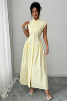 Woman wearing the Limoncello Lane Collared Midi Dress in pale yellow with a textured stripe, pointed collar, cap sleeves, defined waist, and full midi skirt.
