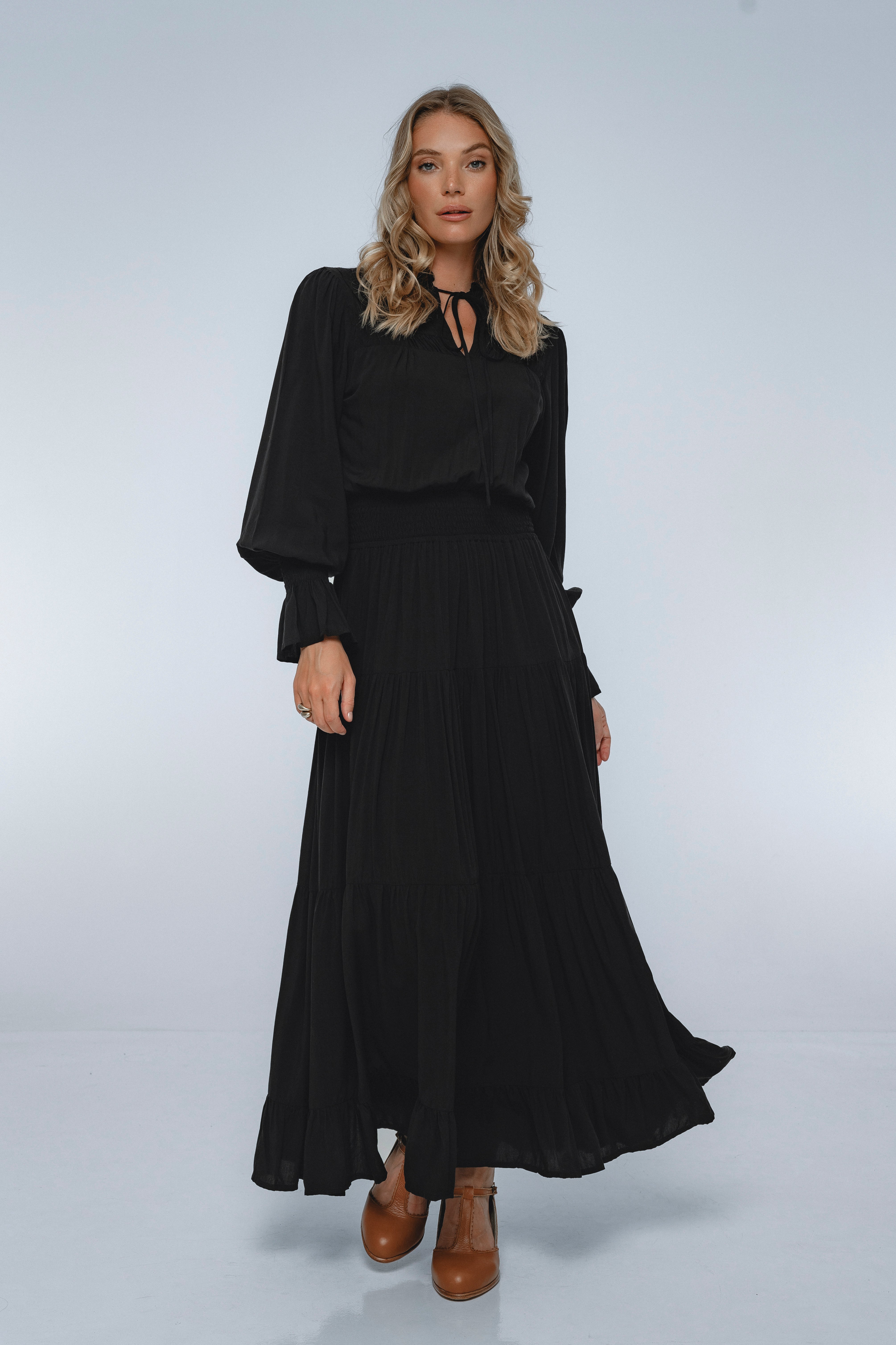 Woman wearing a black dress with long sleeves on a white background