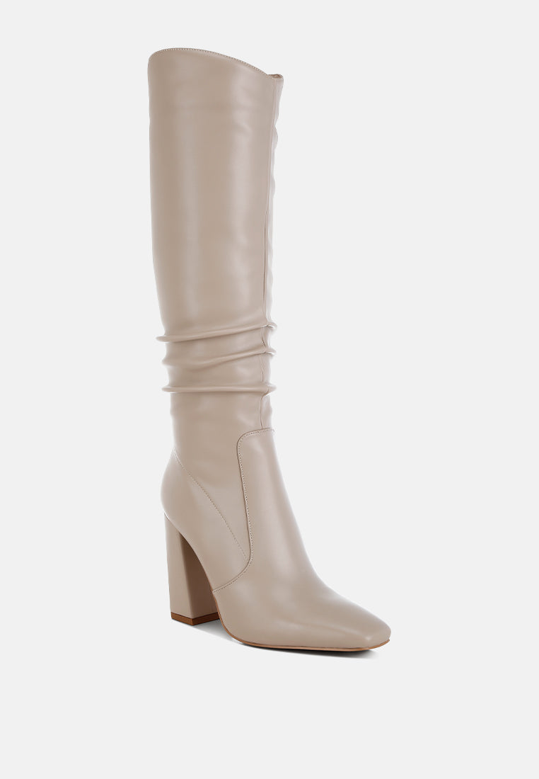 Angled front view of beige Vienna Sculpted Heel Knee High Boots featuring smooth faux leather, tall shaft and high block heel.