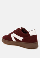 Burgundy sneaker with a white patchwork design on a light gray background