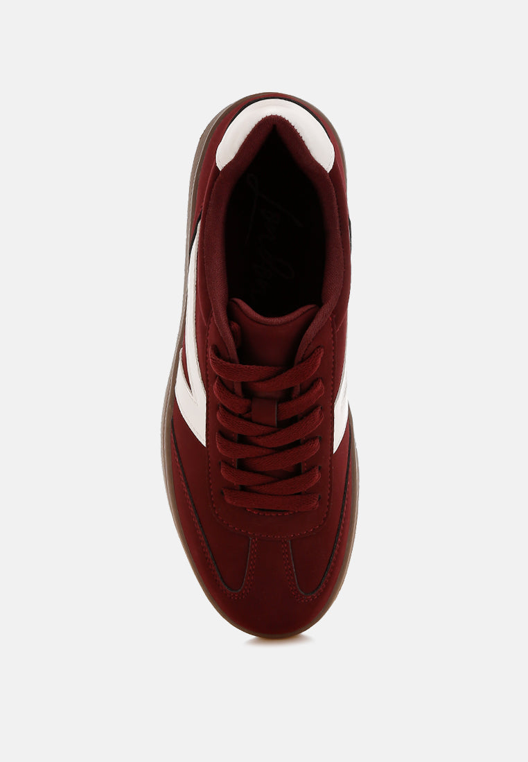 Burgundy sneaker with a white patchwork design on a light gray background  top view