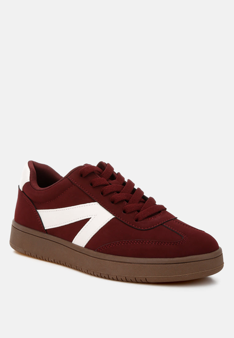 Burgundy sneaker with a white patchwork design on a light gray background