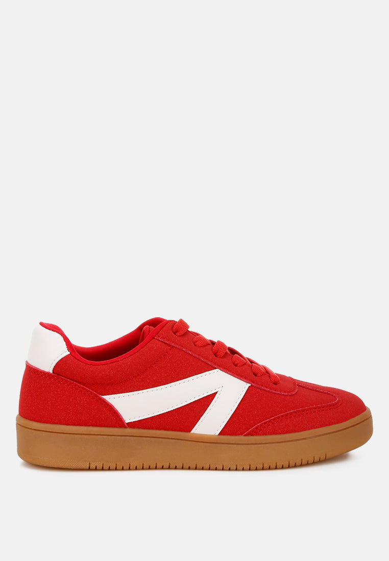 Red sneaker with white patchwork on a light gray background