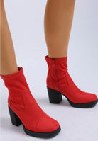Close-up of red platform block heel boots with side zipper.
