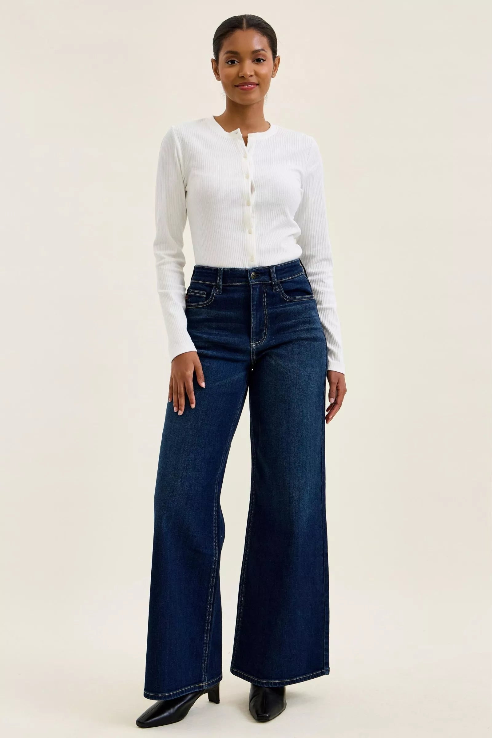 Going Places High Rise Wide Leg Jeans in dark indigo wash styled with a white knit top and boots. 