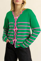 Close-up of V-neck cardigan with pink bow tie closures and scalloped trim