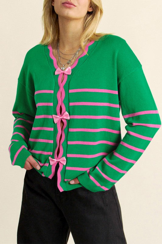 Close-up of V-neck cardigan with pink bow tie closures and scalloped trim
