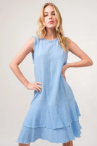 Woman wearing a light blue cotton gauze dress with tiered ruffle hem and sleeveless silhouette | AVAH Collections
