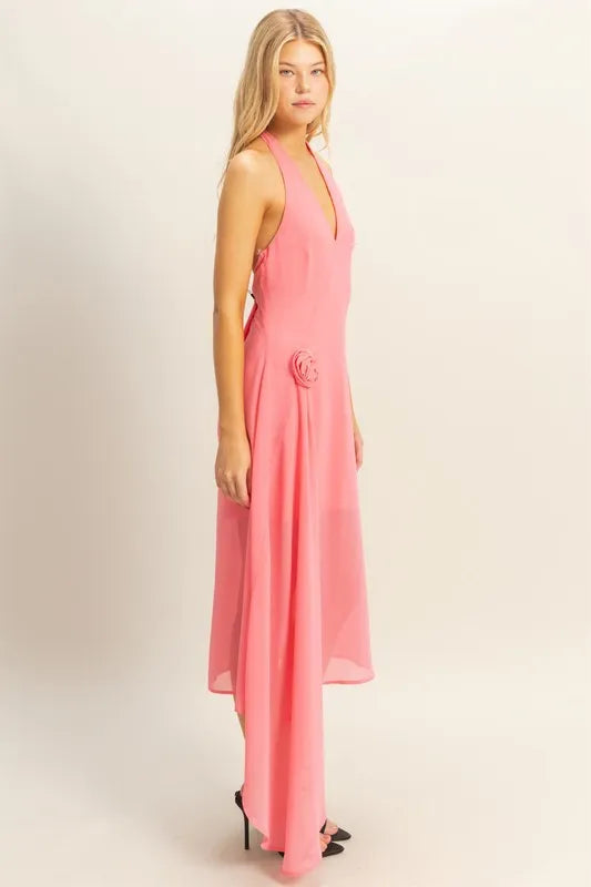 Side view of pink chiffon halter midi dress with rosette hip detail and asymmetrical draped hem
