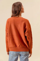 Back view of Copper Meadow Floral Knit Sweater in rust orange with dropped shoulders and ribbed hem.