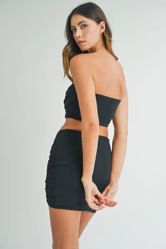 Back view of black strapless crop top and fitted mini skirt set
