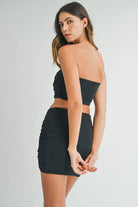 Back view of black strapless crop top and fitted mini skirt set
