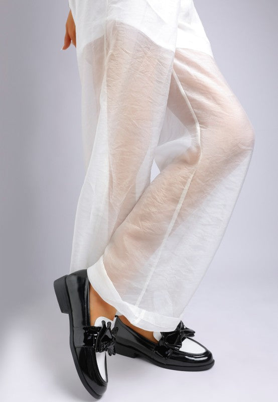 model wearing black and white patent loafers with oversized bow accent
