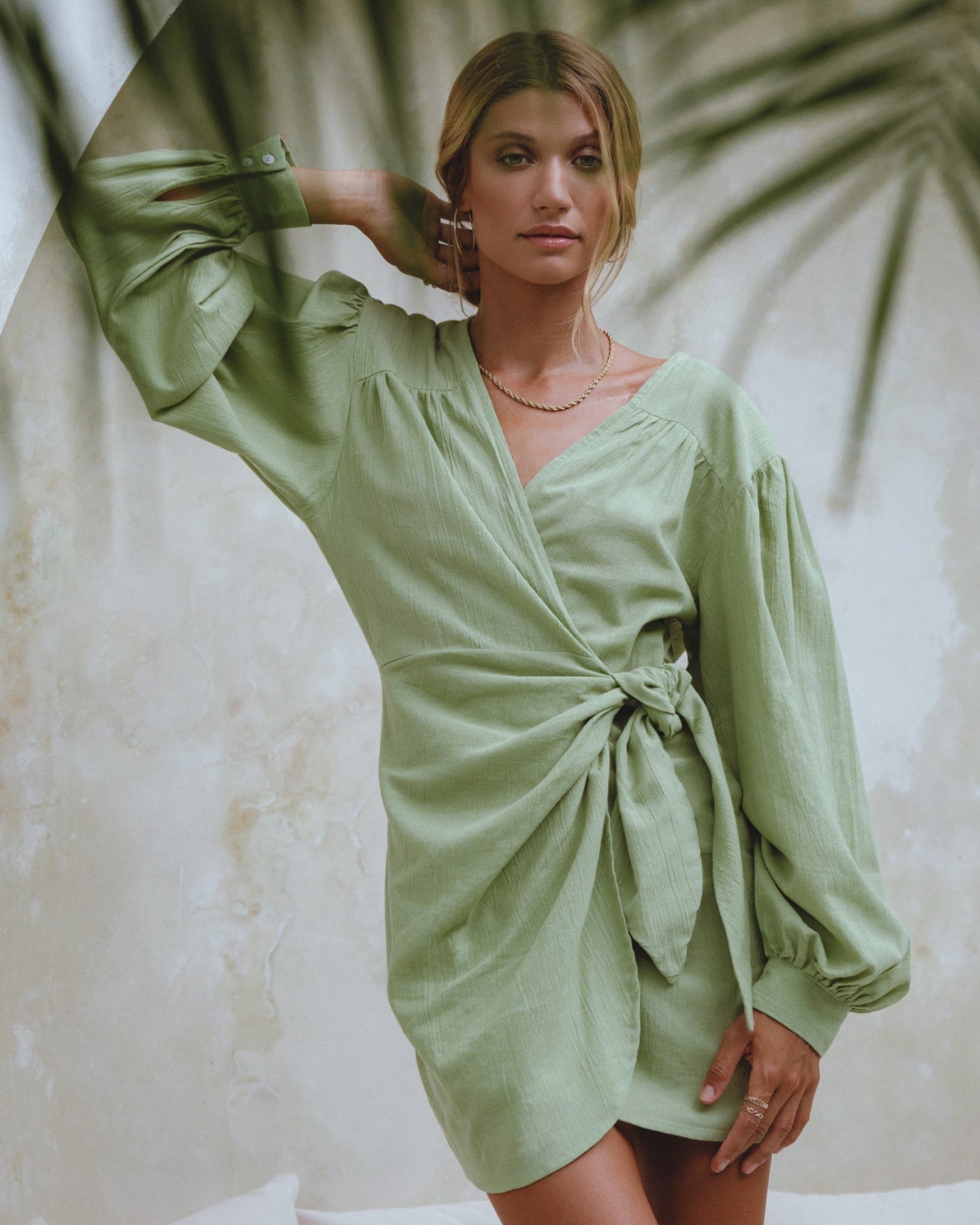 Model wearing a sage green Bali ELF wrap dress with long sleeves inspired by relaxed island living and timeless design.