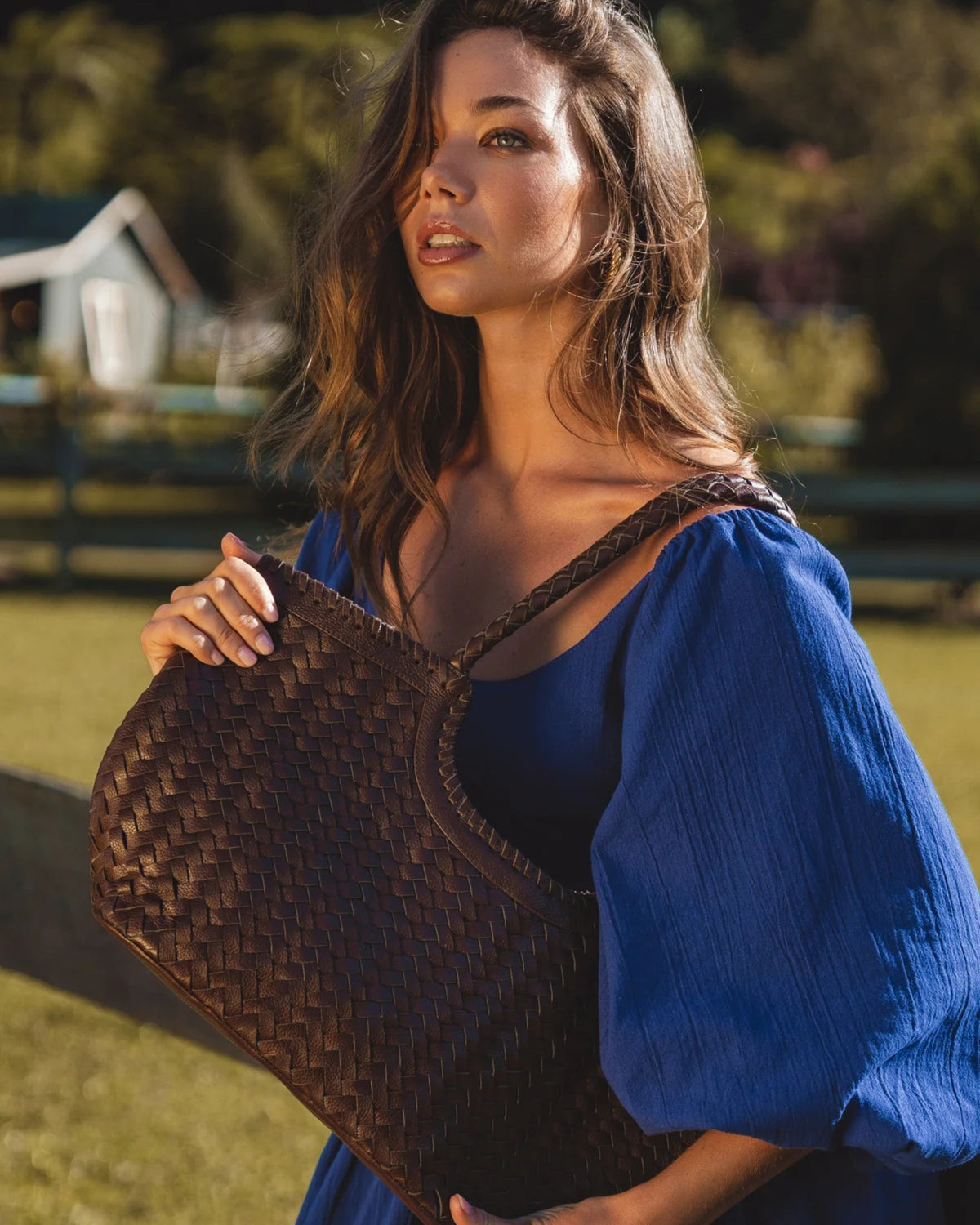 Model in a blue dress carrying a handcrafted woven Bali ELF leather bag