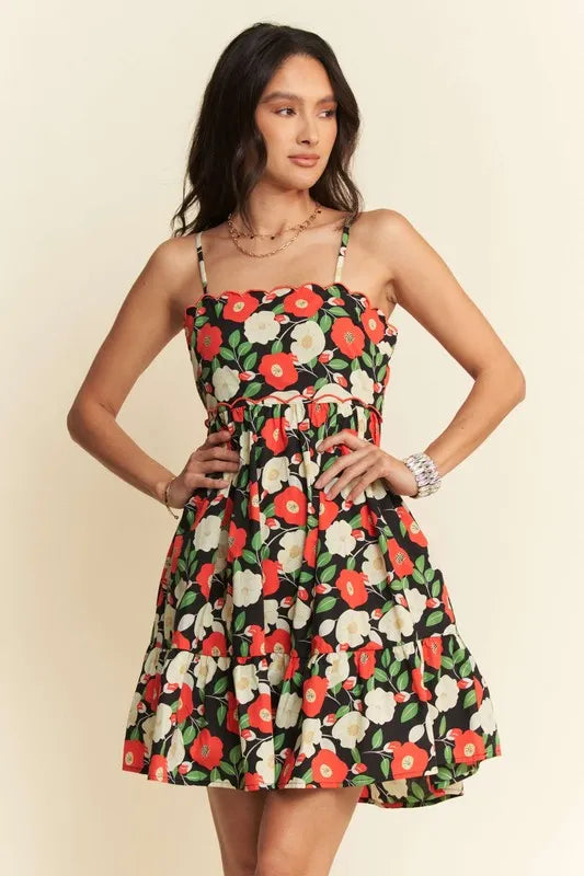 Woman wearing black floral cotton mini dress with red and ivory flowers
