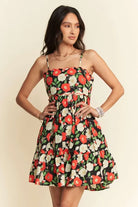 Woman wearing black floral cotton mini dress with red and ivory flowers
