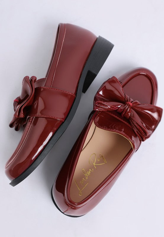close-up of glossy red bow loafers flat lay
