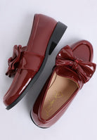 close-up of glossy red bow loafers flat lay
