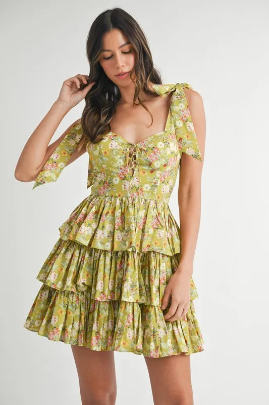 Woman wearing lime green floral tiered mini dress with tie shoulder straps and lace-up bodice front view
