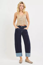 AVAH- Model wearing dark rinse cropped wide leg jeans with oversized contrast cuffs and classic five pocket styling.