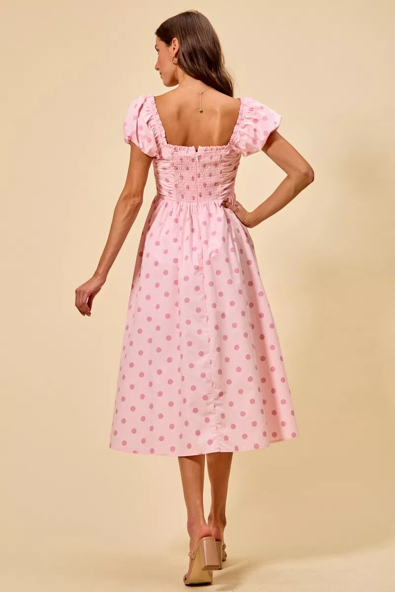 Back view of pink polka dot midi dress featuring a smocked back panel and flowing midi skirt | AVAH Collections

