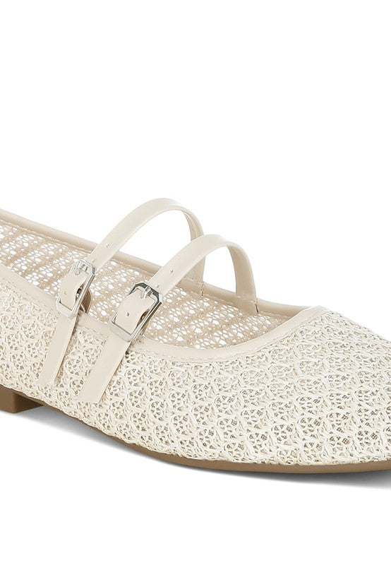 Close-up of beige ballet flats, showing intricate raffia weave and buckle accents.