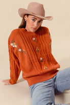 Copper Meadow Floral Knit Sweater styled with light wash jeans, showing relaxed fit and floral embroidery.