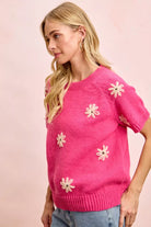 Side view of pink daisy embroidered short sleeve sweater with crew neckline and ribbed trim
