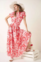 Coral floral two piece maxi skirt set featuring a short sleeve top with waist tie detail and tiered maxi skirt styled with a wide brim hat.