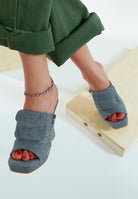 Model wearing denim open-toe shoes with a white background