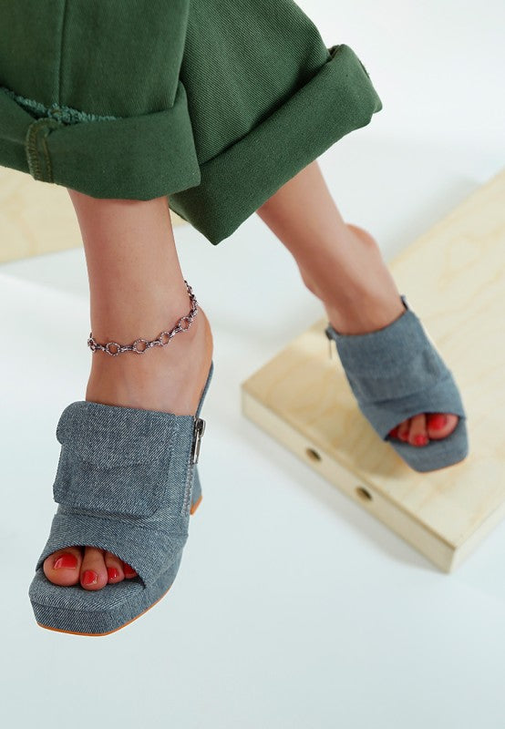 Model wearing denim open-toe shoes with a white background